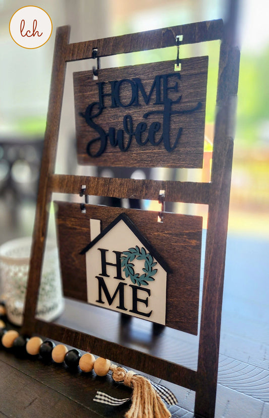 Wooden ladder picture frame hanger displaying home sweet and home signs in a rustic style