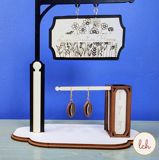 Hand painted wooden earrings displayed on a creative wooden stand with decorative floral sign