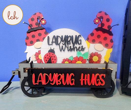 Wooden wagon insert with ladybug and gnome decorations and signs reading Ladybug Wishes and Ladybug Hugs