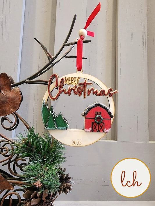 2023 Merry Christmas wooden ornament with red barn, green trees, and red ribbon hanger