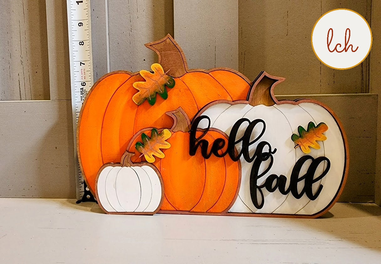 Decorative wooden pumpkins with hello fall sign and autumn leaves for fall decoration