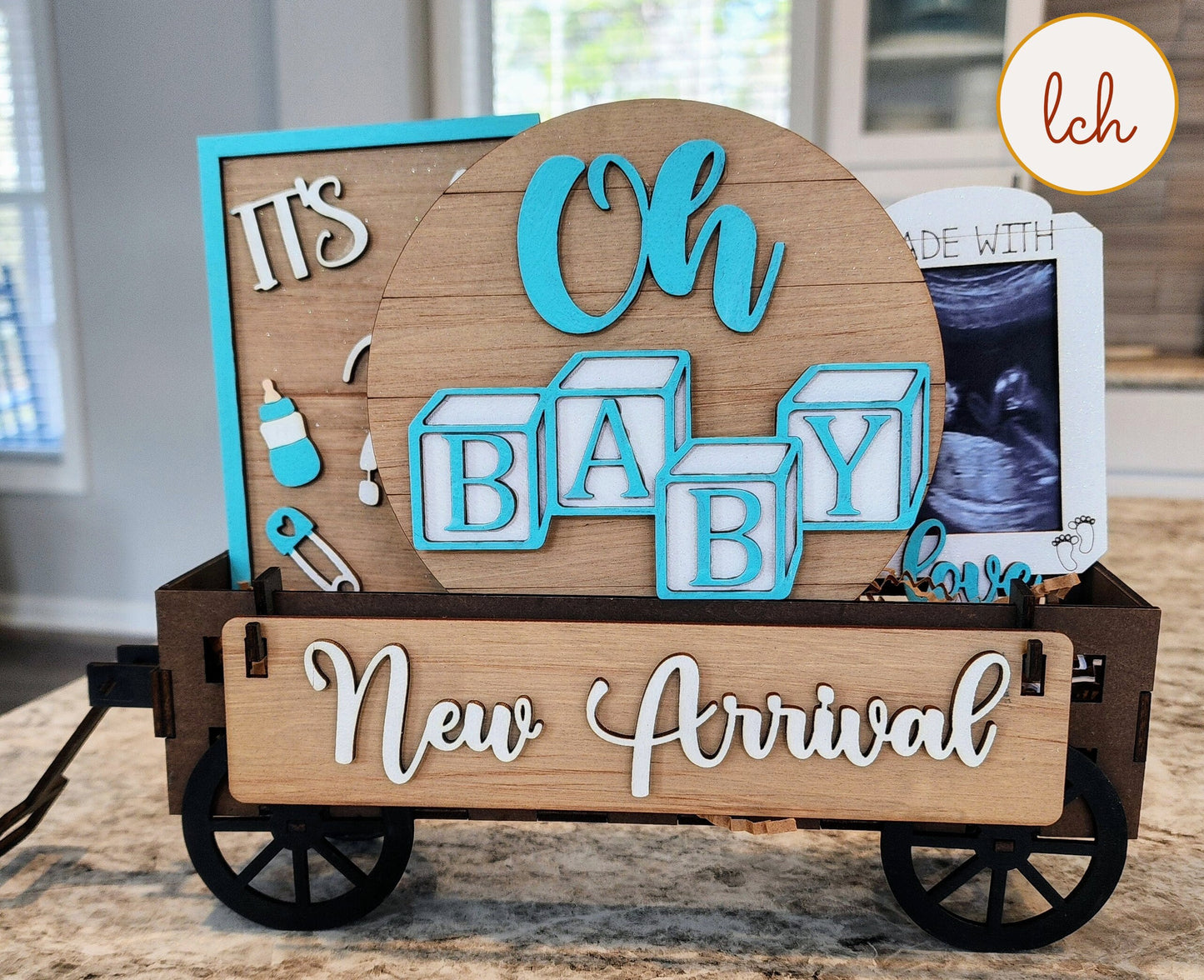 Wooden wagon insert with New Arrival sign and baby-themed decorations for baby announcement