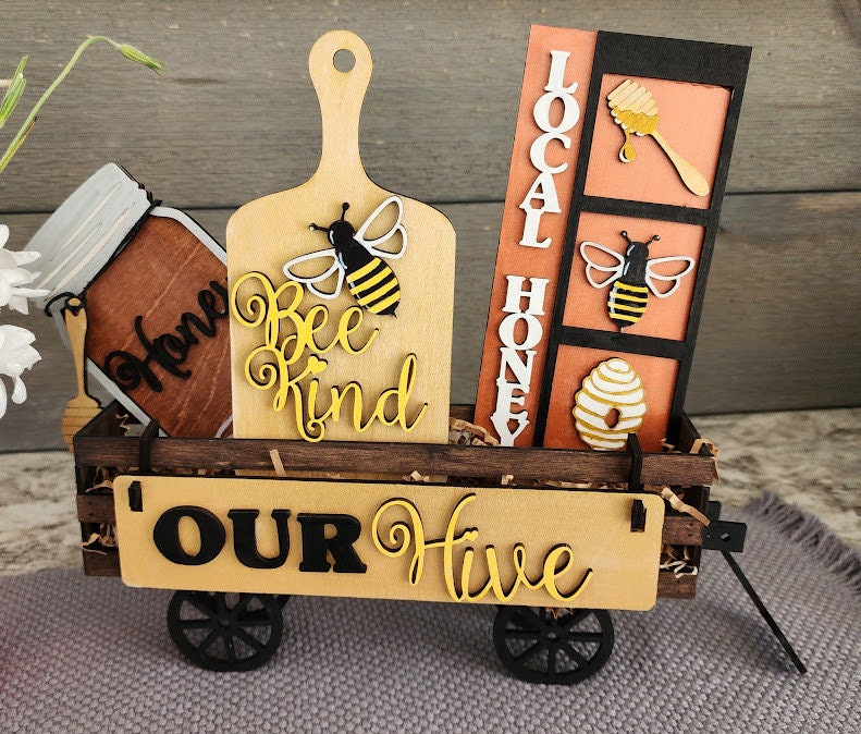 Wooden wagon insert with bee and honey-themed decorative pieces including Bee Kind sign and Local Honey wall art