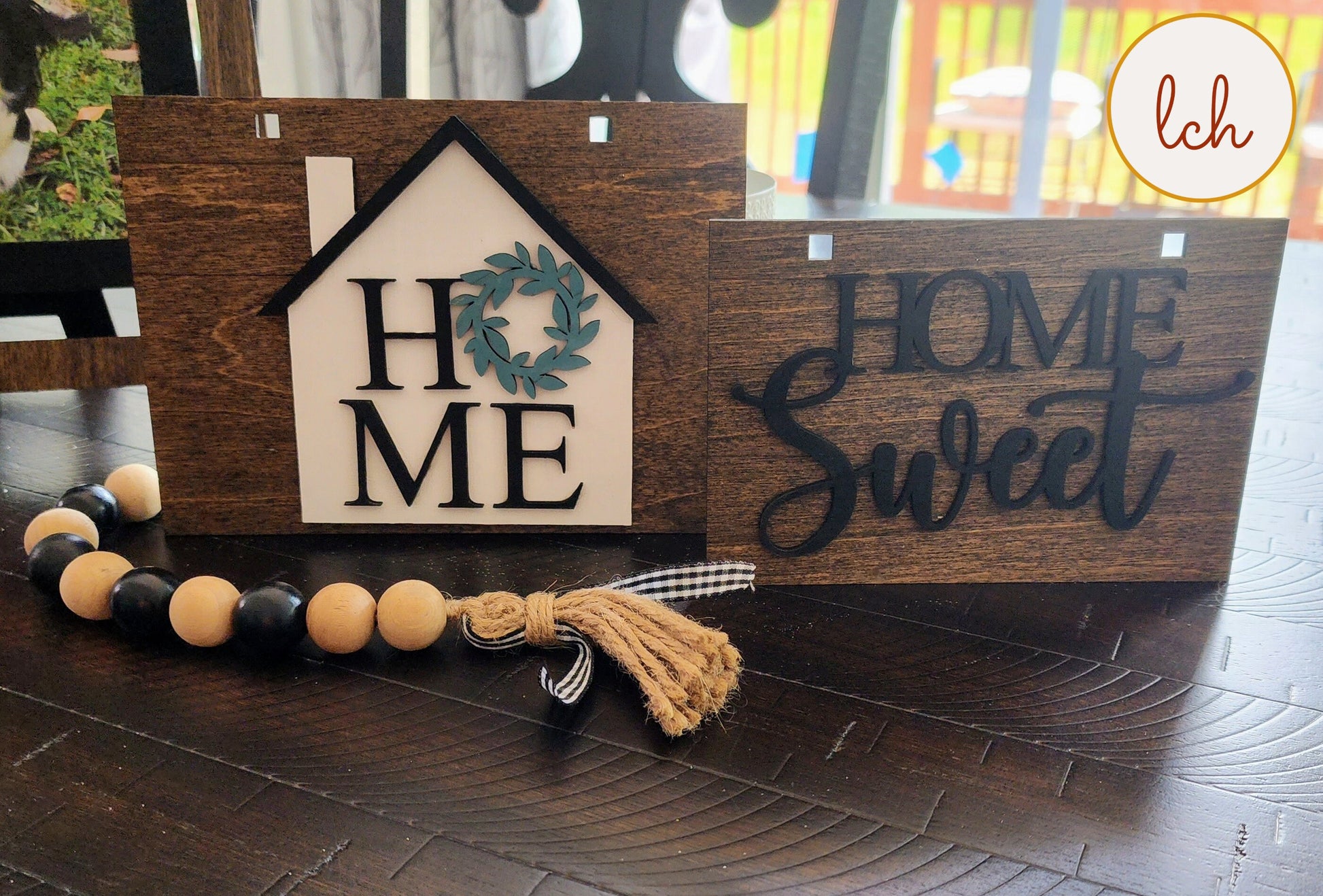 Wooden ladder picture frame hanger displaying home and home sweet decorative signs on dark wood