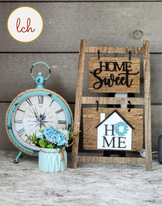 Wooden ladder picture frame hanger with home sweet signs next to vintage clock and blue flowers
