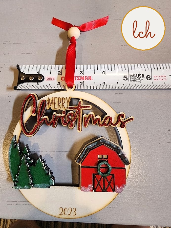2023 Merry Christmas wooden ornament with red barn and green trees hanging on red ribbon